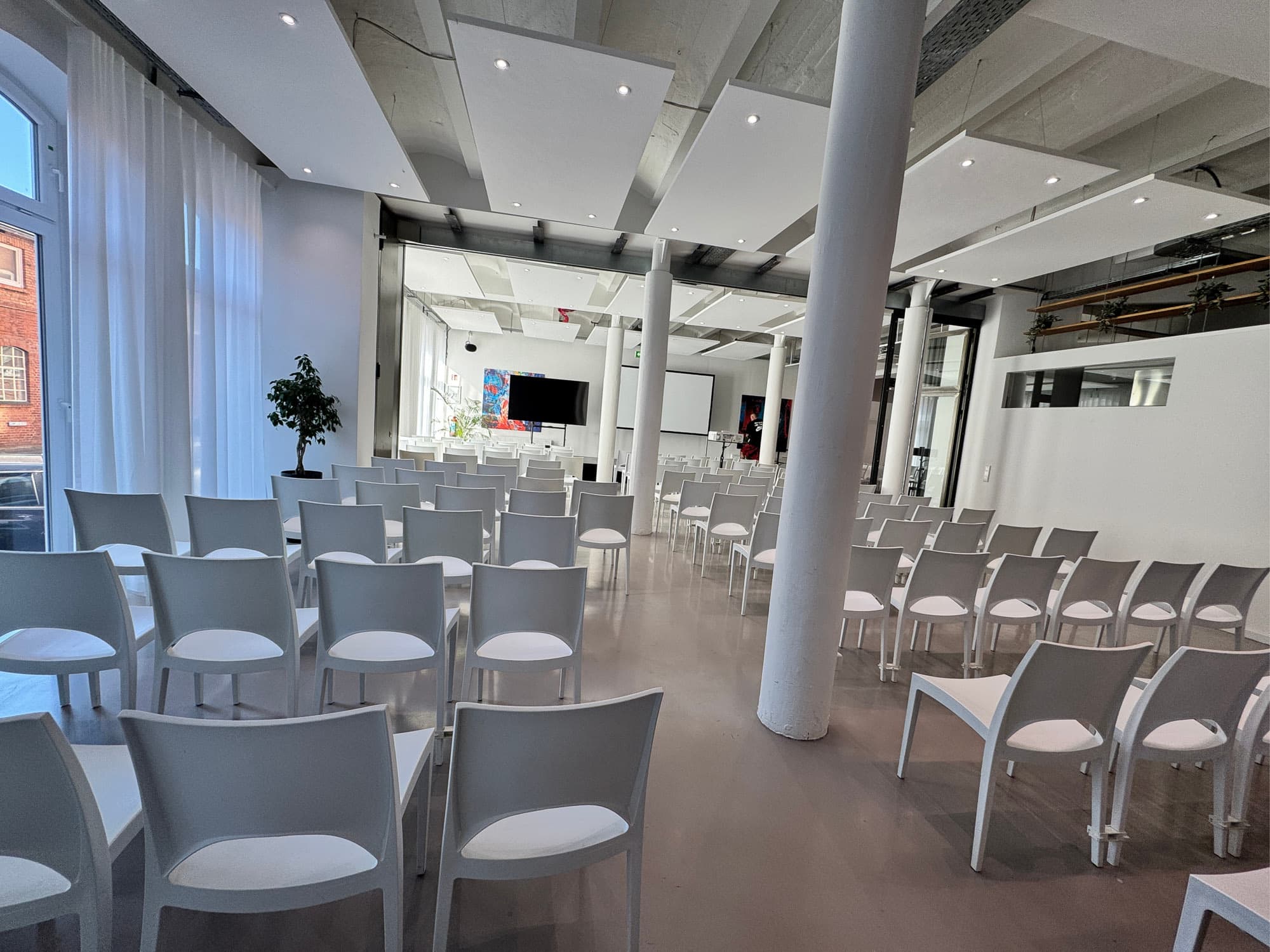 Tagungsbestuhlung in Reihen zwischen weißen Säulen, Tageslicht durch Sprossenfenster – Firmenevents im REST2RENT Hamburg